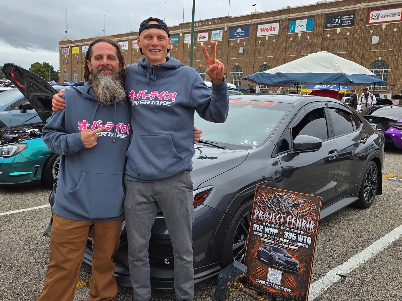 Don with Art Petrakov, Overtake co-founder, beside the car and the Project Fenrir show sign